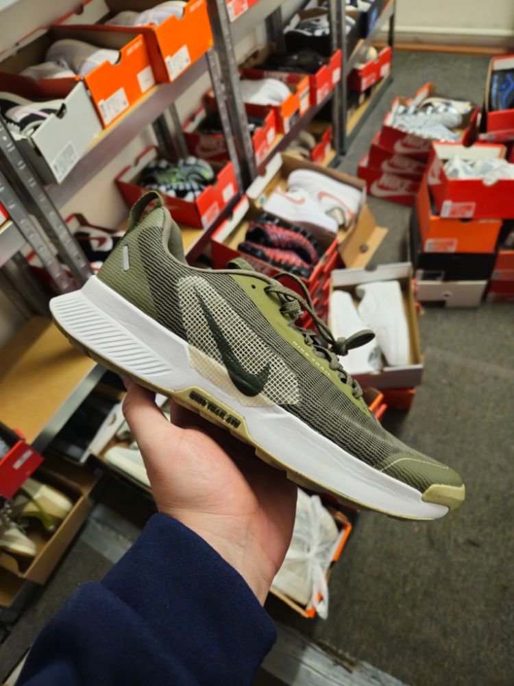 Tenisky Nike v ruke, v pozadí police KicksByDavid